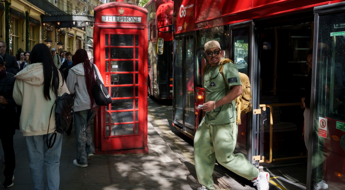 london, black man in light green throusers and shirt, red telephone booth
