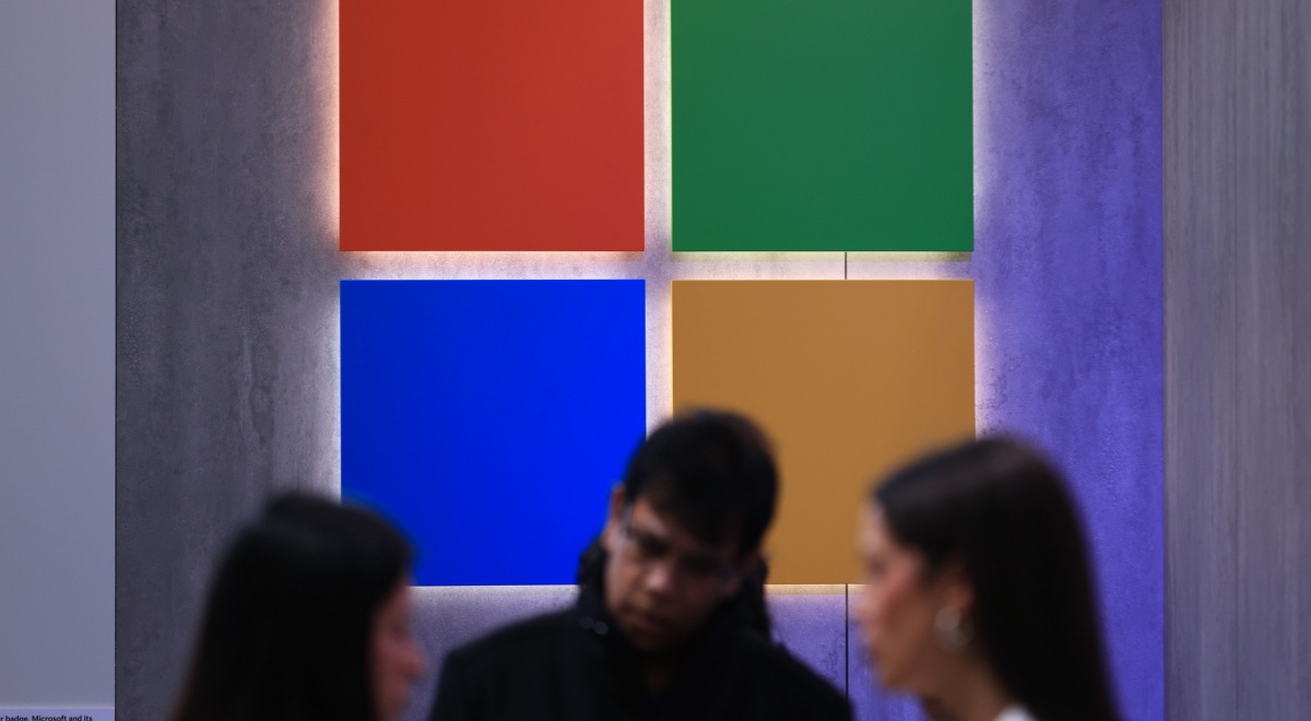 microsoft logo, red, green, blue, yellow squares, two white blurry women, one white blurry man.