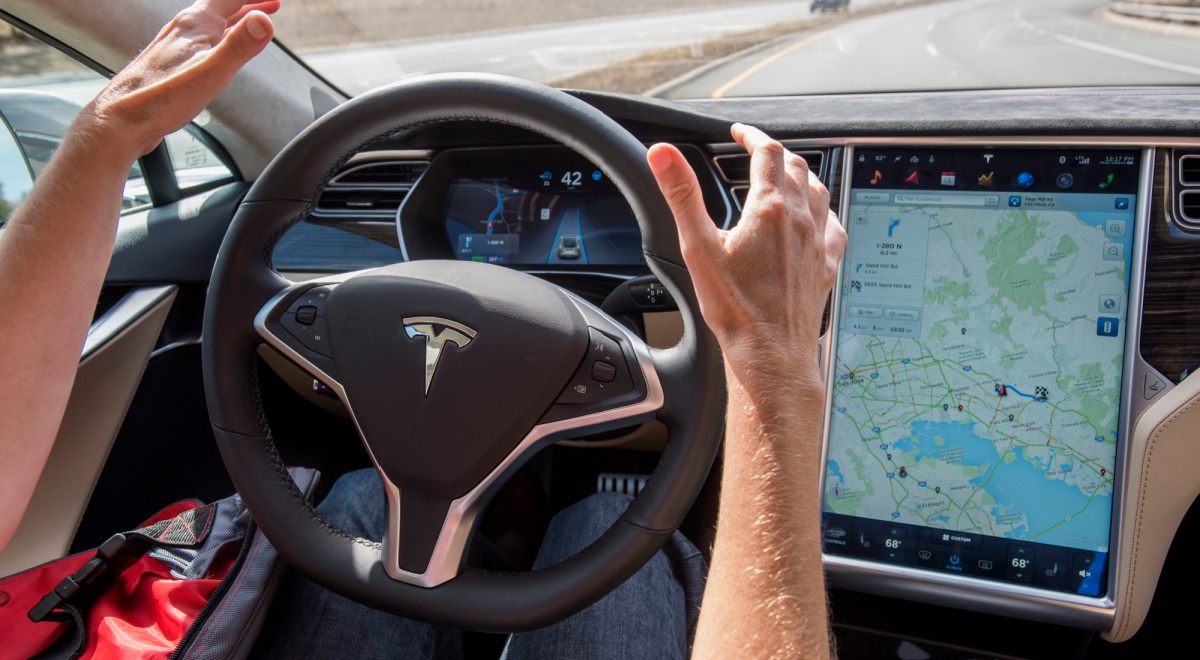 white man hands, black tesla wheel, screen with map on it, car front window, bright red shirt