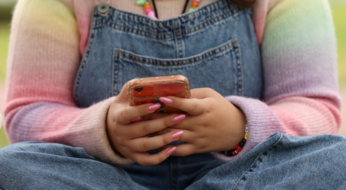 pink nails, smartphone, jeans, rainbow color top