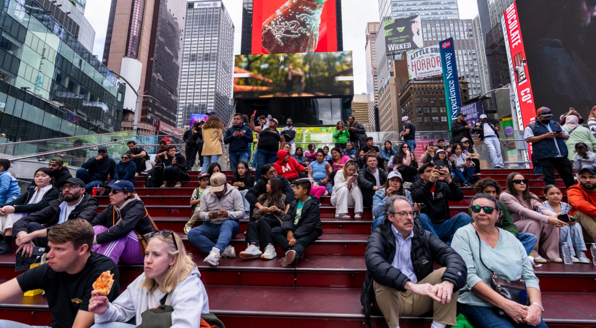 people sitting on stairs, time square, coca cola red billboard, tall glass buildings