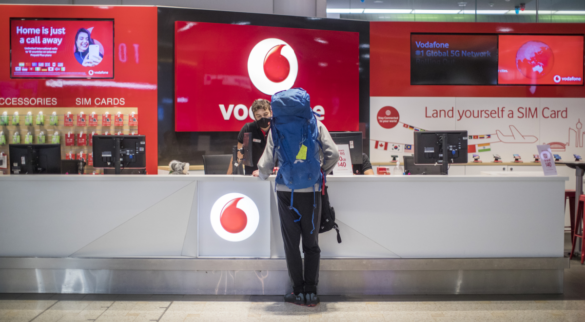 vodafone red kiosk, traveler in huge light blue backpack,, 