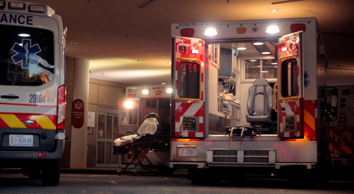 ambulance bay by hospital, two white ambulance cars, one with back door open, light blue seat