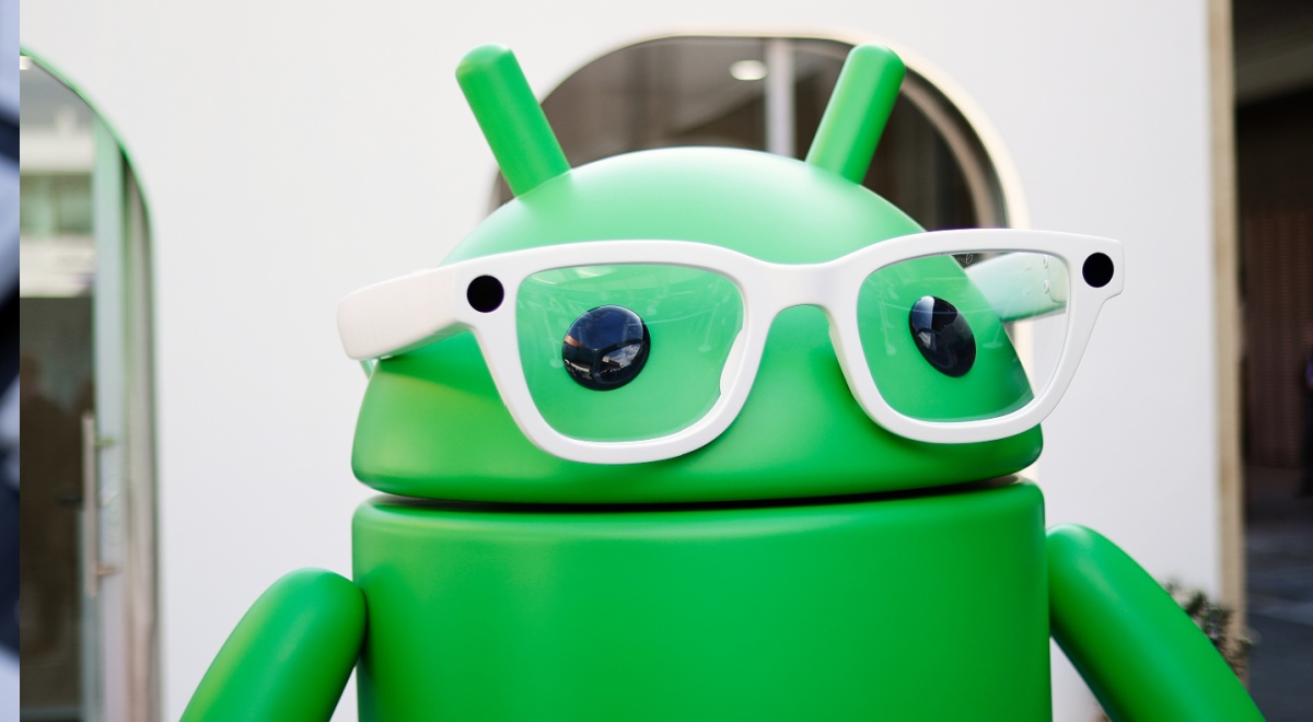 Green stylized Google Android mascot, white frame glasses, black eyes, alien ears