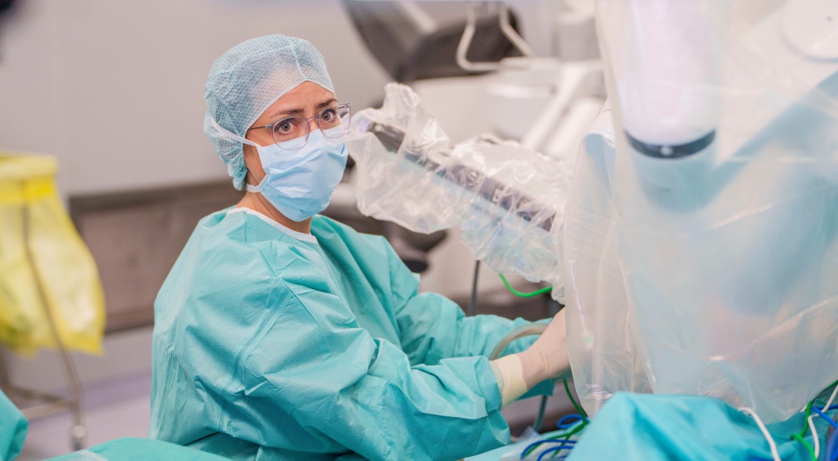 female doctor, light blue face mask and hair net, light mint scrubs, glasses, operating room,