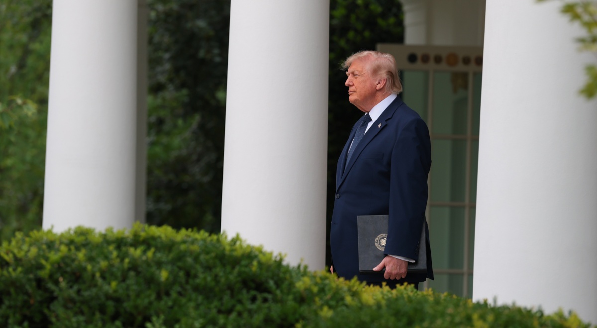 donald trump, dark suit, white collar shirt, profile, he stands in colonnade at the White House