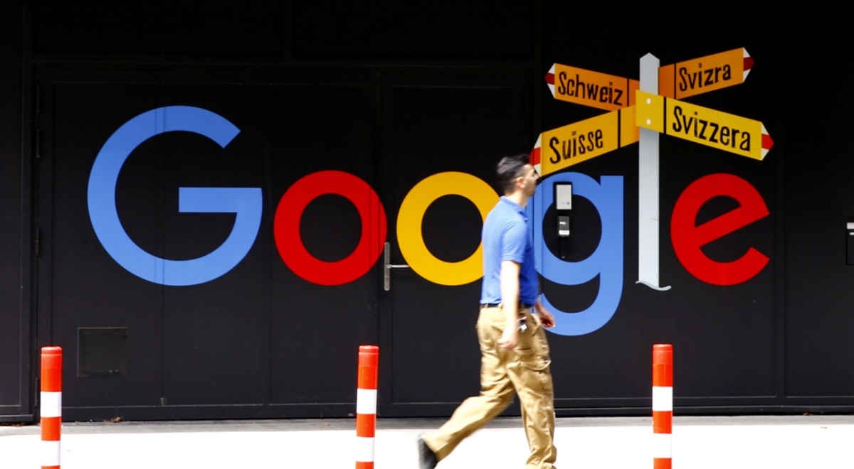 khaki throusers, blue t-shirt, white male, google logo, light orange pointers to Switzerland.