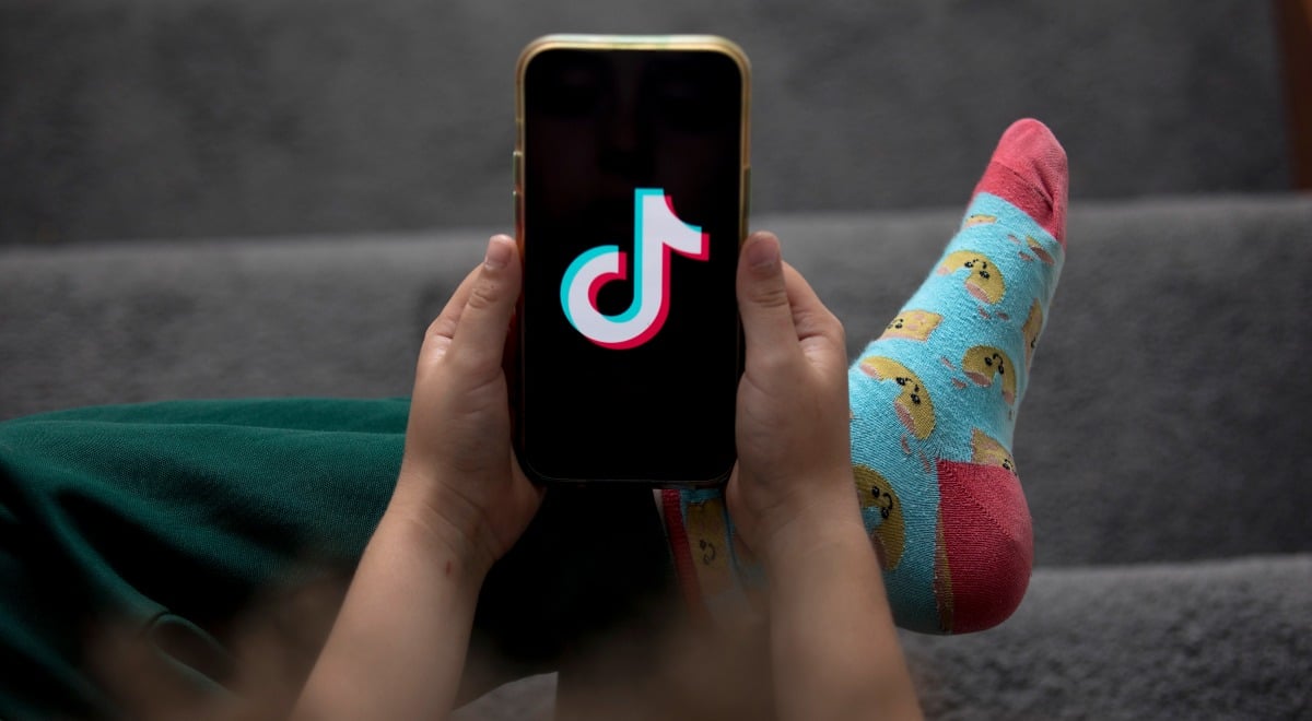 A child holds a smartphone displaying the TikTok logo in an arranged photograph in Sydney, Australia