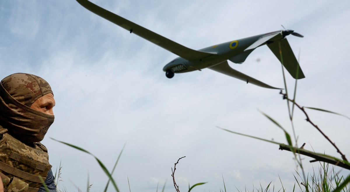 white soldier in field with tall grass, blue sky, white clouds, huge military drone in the sky