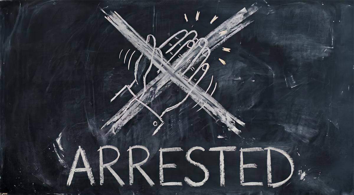 A chalkboard with clapping hands drawn and crossed out, the word "arrested"