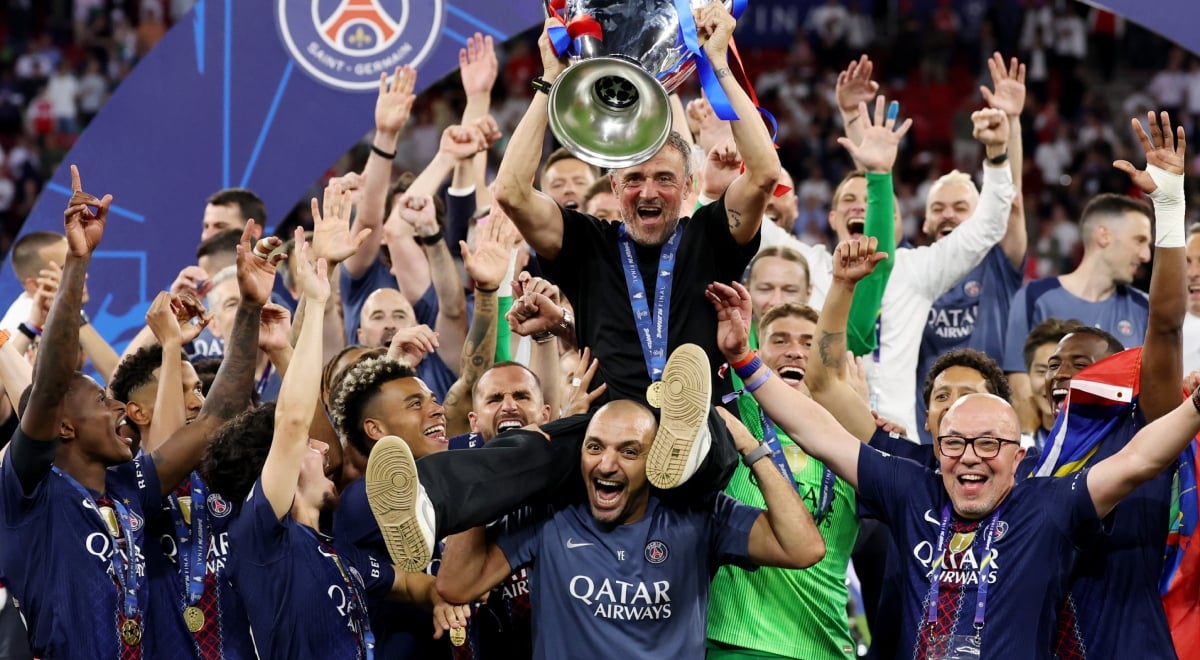 Luis Enrique sits on man's shoulder, men wearing  paris saint-germain club shirts, hands up