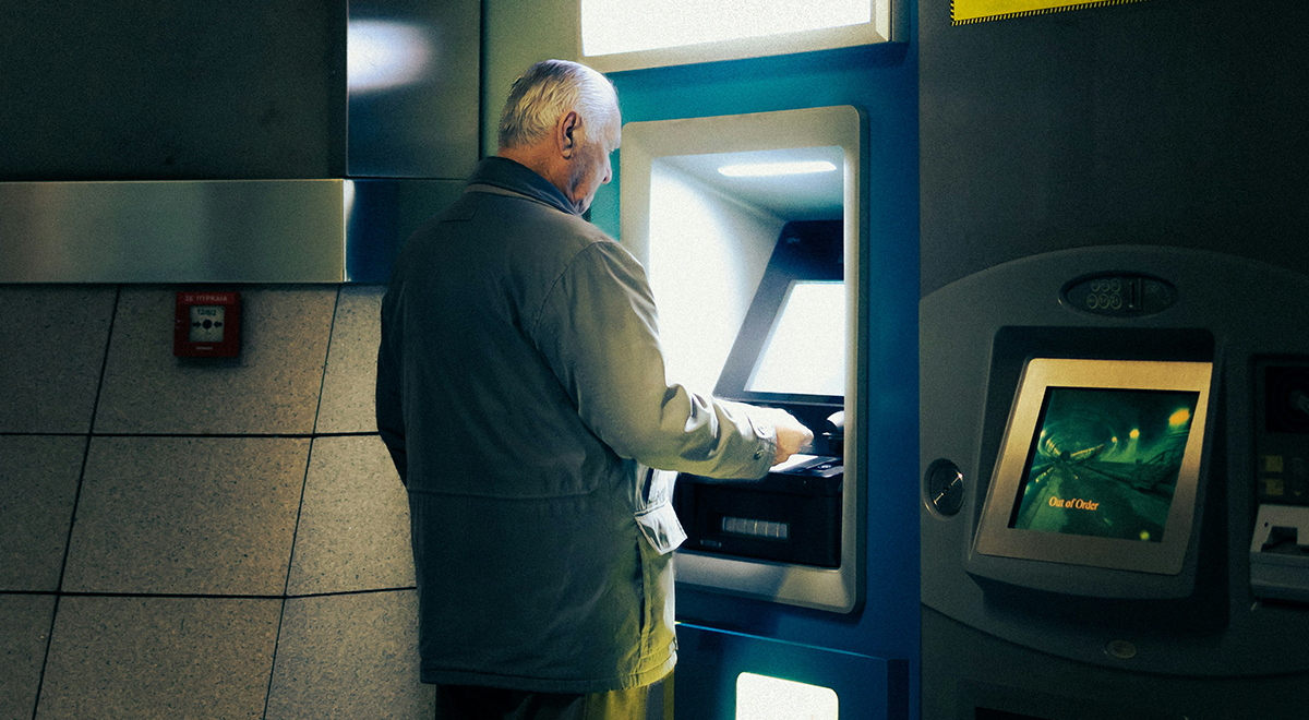 older man standing at the atm
