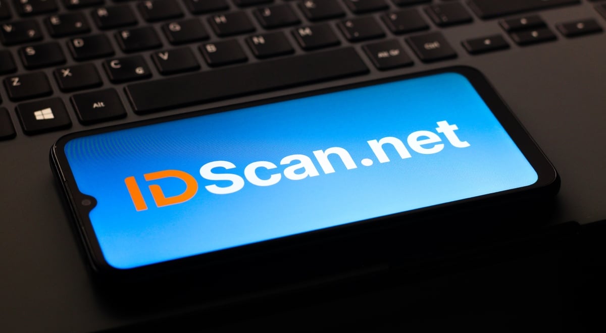 IDScan.net logo is on a smartphone screen, black keyboard in the back,