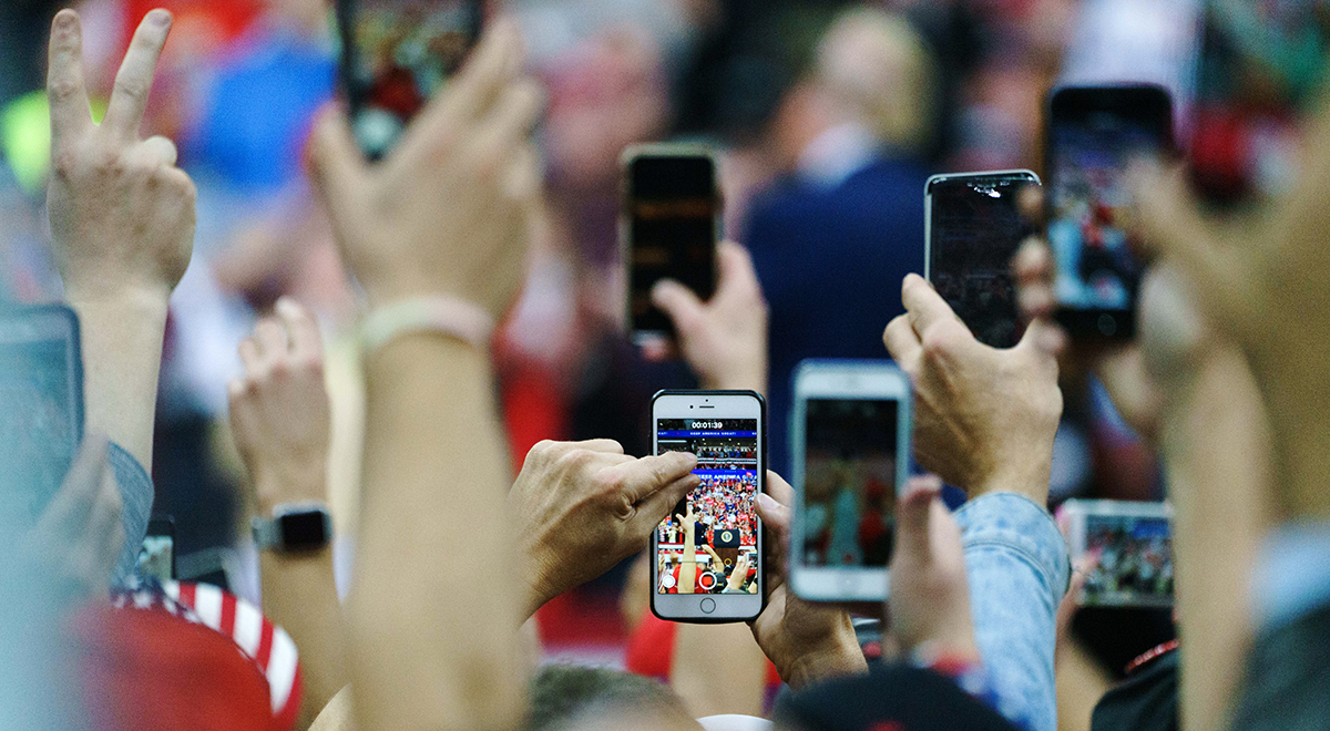 Attendees hold up their smartphones to take videos during a rally with U.S. President Donald Trump in Minneapolis