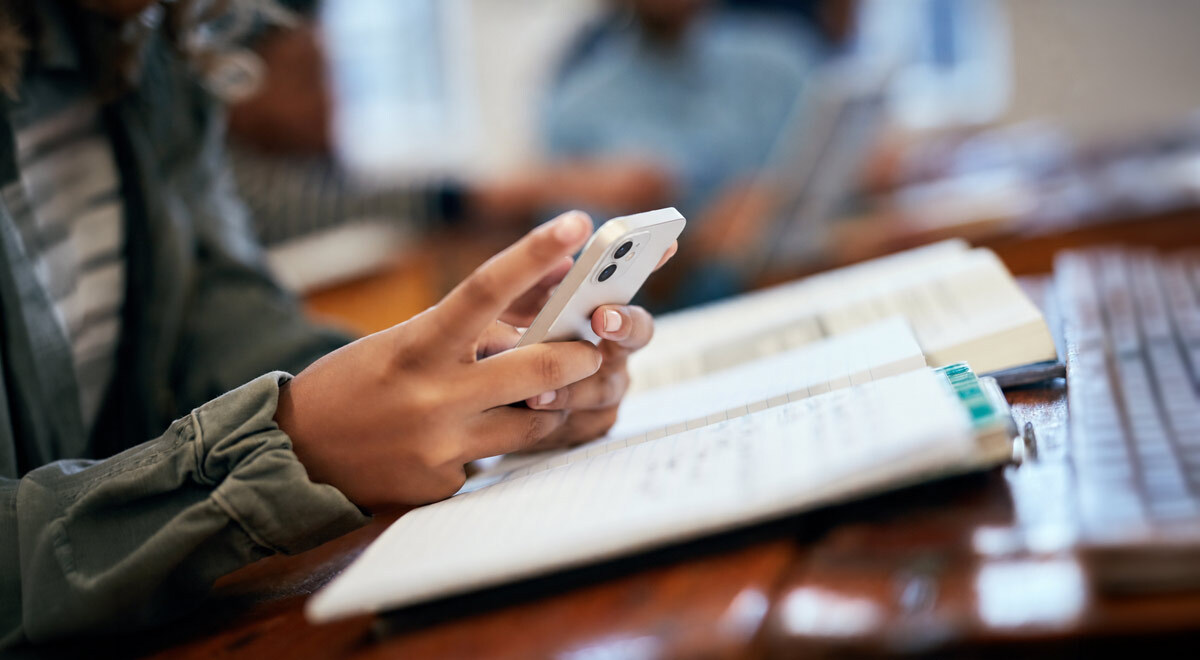 A student scrolling on a phone and studying