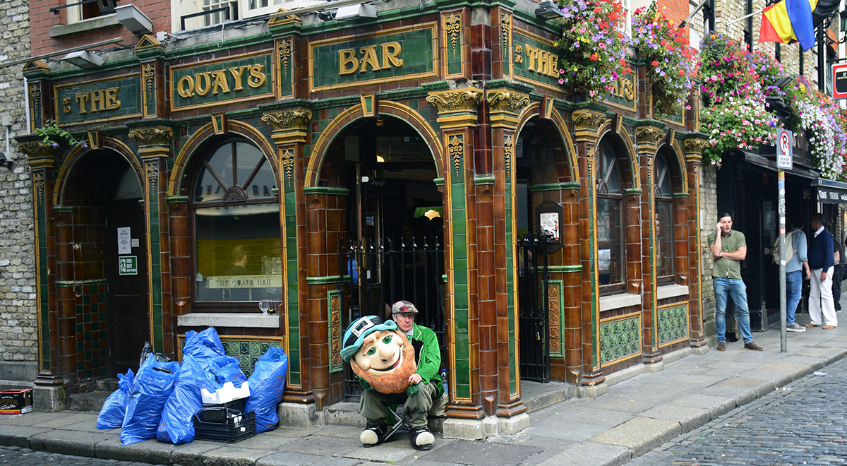 A man dressed in a leprechaun costume hired to attract customers to a Dublin, Ireland, pub takes a break in front of the pub in Dublin's Temple Bar district.