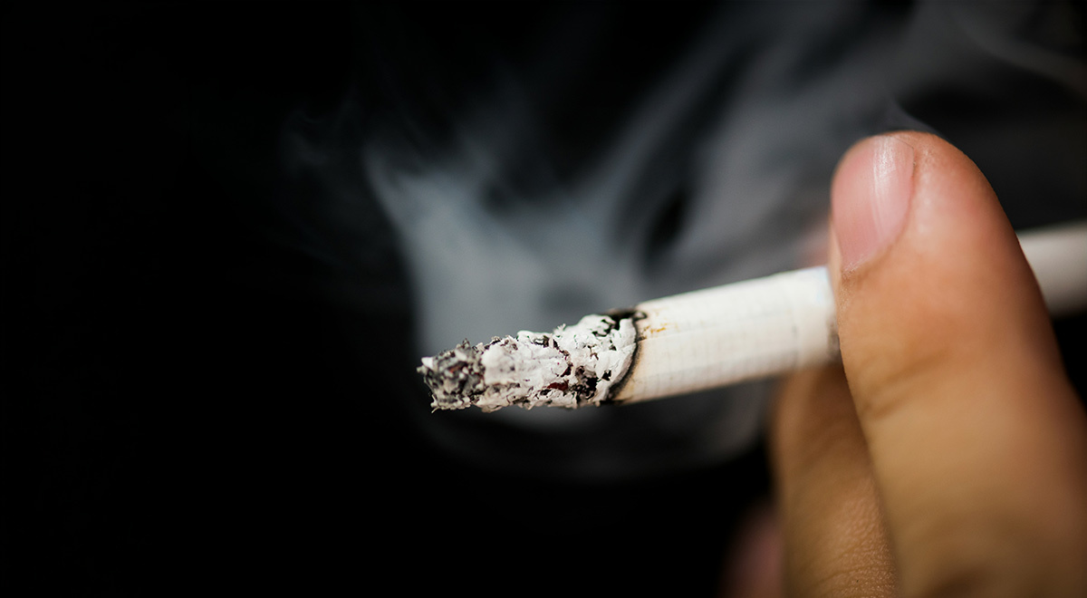 A person's hand holding a cigarette.
