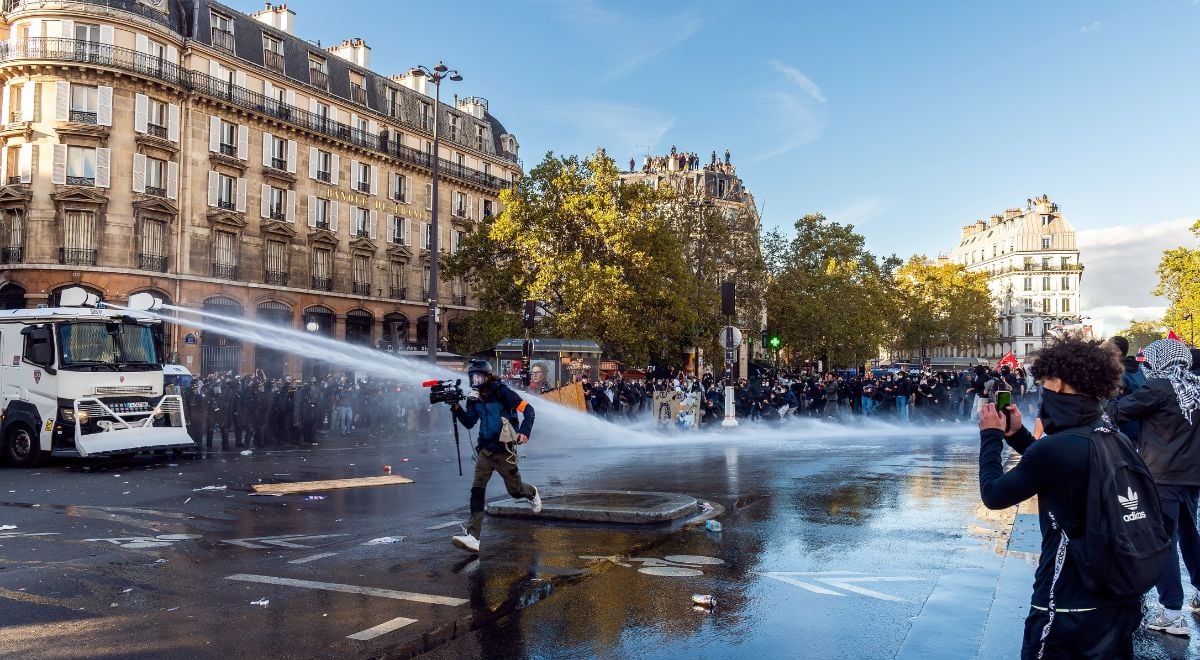 Videographer runs through water cannon while student films with phone