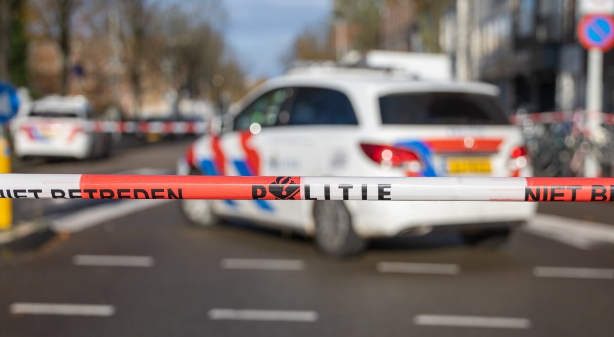 police security tape reading "politie" in Dutch; police car in the background
