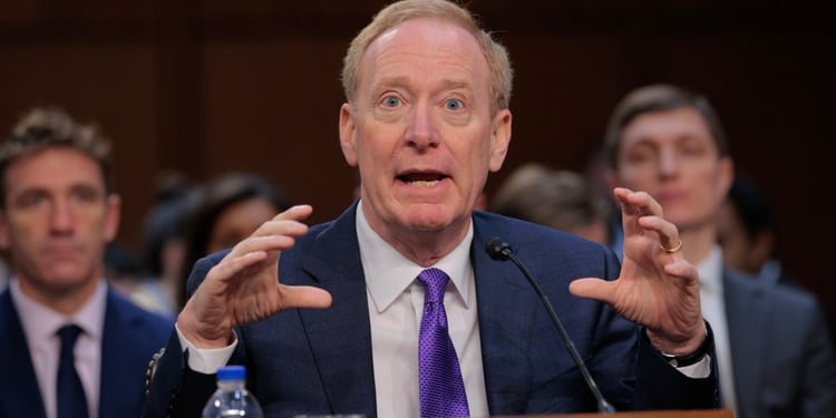 Microsoft Corporation President and Vice Chair Brad Smith with two men in the back