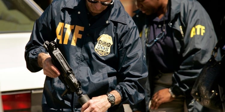 2 ATF agents wearing jackets with logo holding guns