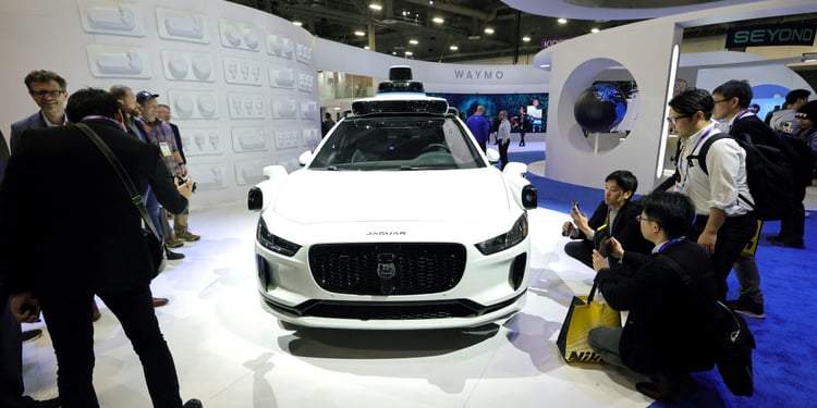 white Jaguar car on white pedestal, people around in black outfits take pictures of it 