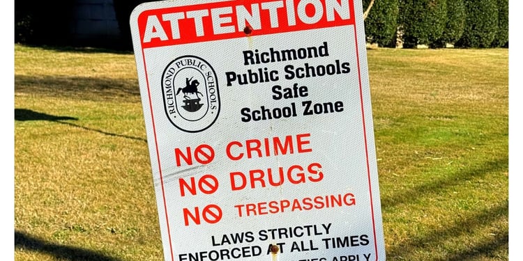 Richmond City Public School sign in forefront, high school in background