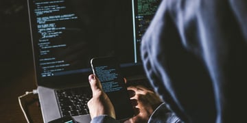 Anonymous person in the hood sitting in front of computer