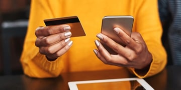 woman holding credit card and smartphone