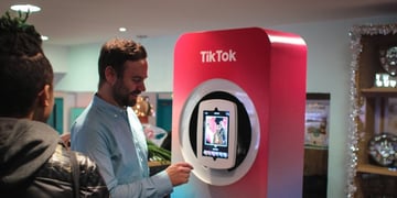 A man in from of TikTok screen and logo
