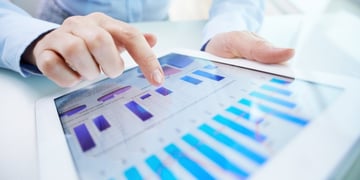 Human hand pointing at touchscreen with business document with graphs