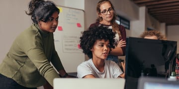 women in work environment discusing by computers