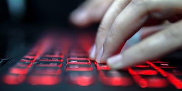 Teenage Hacker Girl Attacks Corporate Servers in Dark, Typing on Red Lit Laptop Keyboard. Room is Da