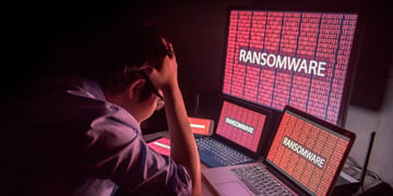 Young Asian male frustrated, confused and headache by ransomware attack on desktop screen, notebook 