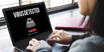 Woman looking at computer screen with inscription Virus Detected