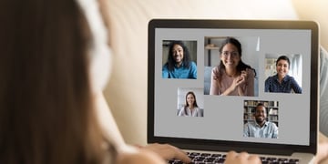 Person looking at PC screen and having a live meeting with multiple people