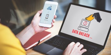 Person using laptop with Data breach inscription on screen with one hand and uploading on mobile on 