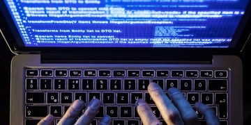 fingers typing on laptop keyboard and blue screen with many inscriptions