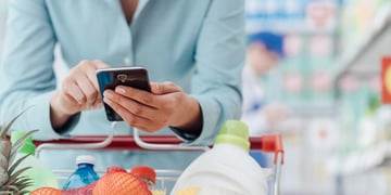 woman with cart looking at mobile
