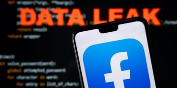 Facebook app logo seen on the smartphone and blurred DATA LEAK word with a brute force script on the