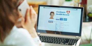 Seen from behind woman at home in sunny day using a cell phone and checking electronic health record