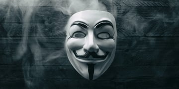 Studio shot of a Anonymous Vendetta mask with smoke on wood
