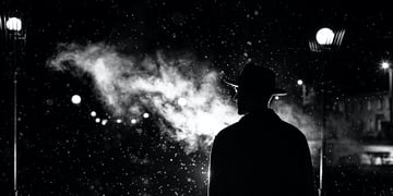 dark silhouette of a man in a hat in the rain on a night street in a city in the style of Noir