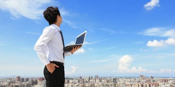 Young business man using laptop and looking at blue sky
