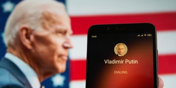 Smartphone with Vladimir Putin contact seen on it's screen and Joe Biden seen on the background.