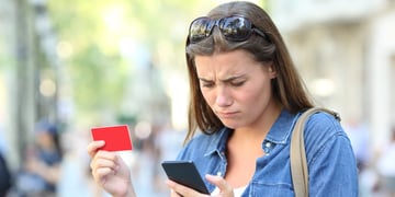 Worried girl having problem paying online with credit card and smart phone in the street