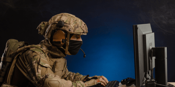 Soldier in full combat gear sat at computer