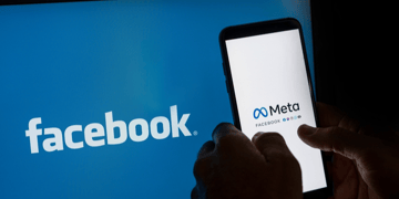 Black gloved hand holding mobile phone saying Meta