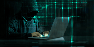 Hooded person using laptop in a matrix background