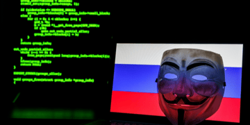 V for Vendetta mask against Russian flag on laptop with Matrix style coding in background